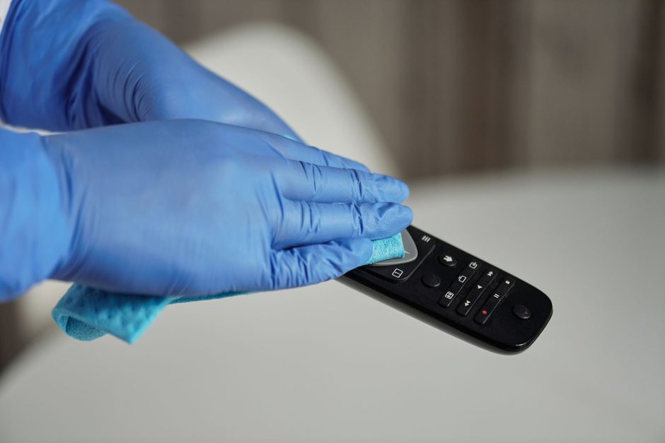 Photo by Matilda Wormwood on Pexels Blue-gloved hand wiping a remote control with disinfectant spray nearby. Photo by Matilda Wormwood on Pexels