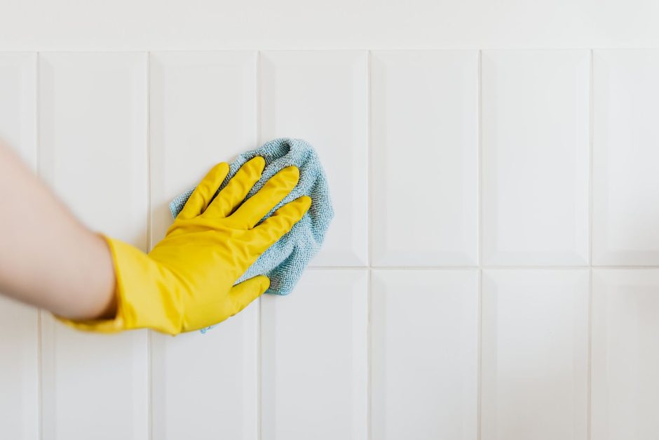 Photo by https://kaboompics.com/ on Pexels Gloved hand scrubbing a white tiled wall with a blue sponge to remove mould. Photo by https://kaboompics.com/ on Pexels