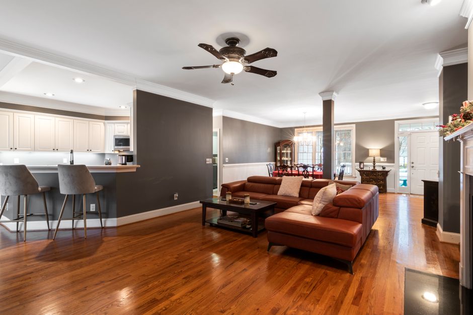 Elegant living room with modern leather sofa, ceiling fan, and open kitchen area.
