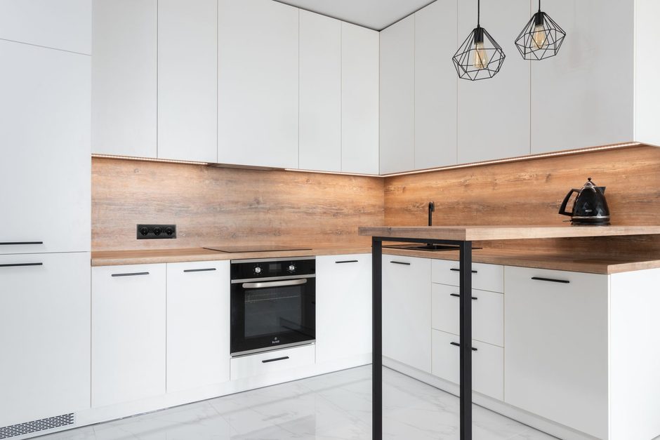 Photo by Max Vakhtbovych on Pexels Modern white kitchen with new cabinets, built-in oven and wood backsplash in a renovated home. Photo by Max Vakhtbovych on Pexels