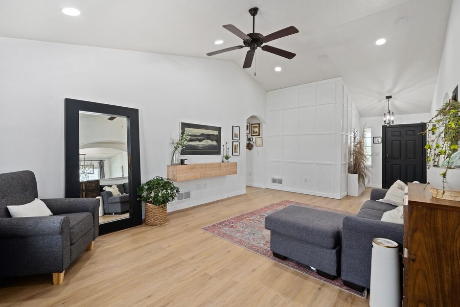 Modern living room with black ceiling fan above grey sofa and wooden floor. Photo by hi room on Pexels